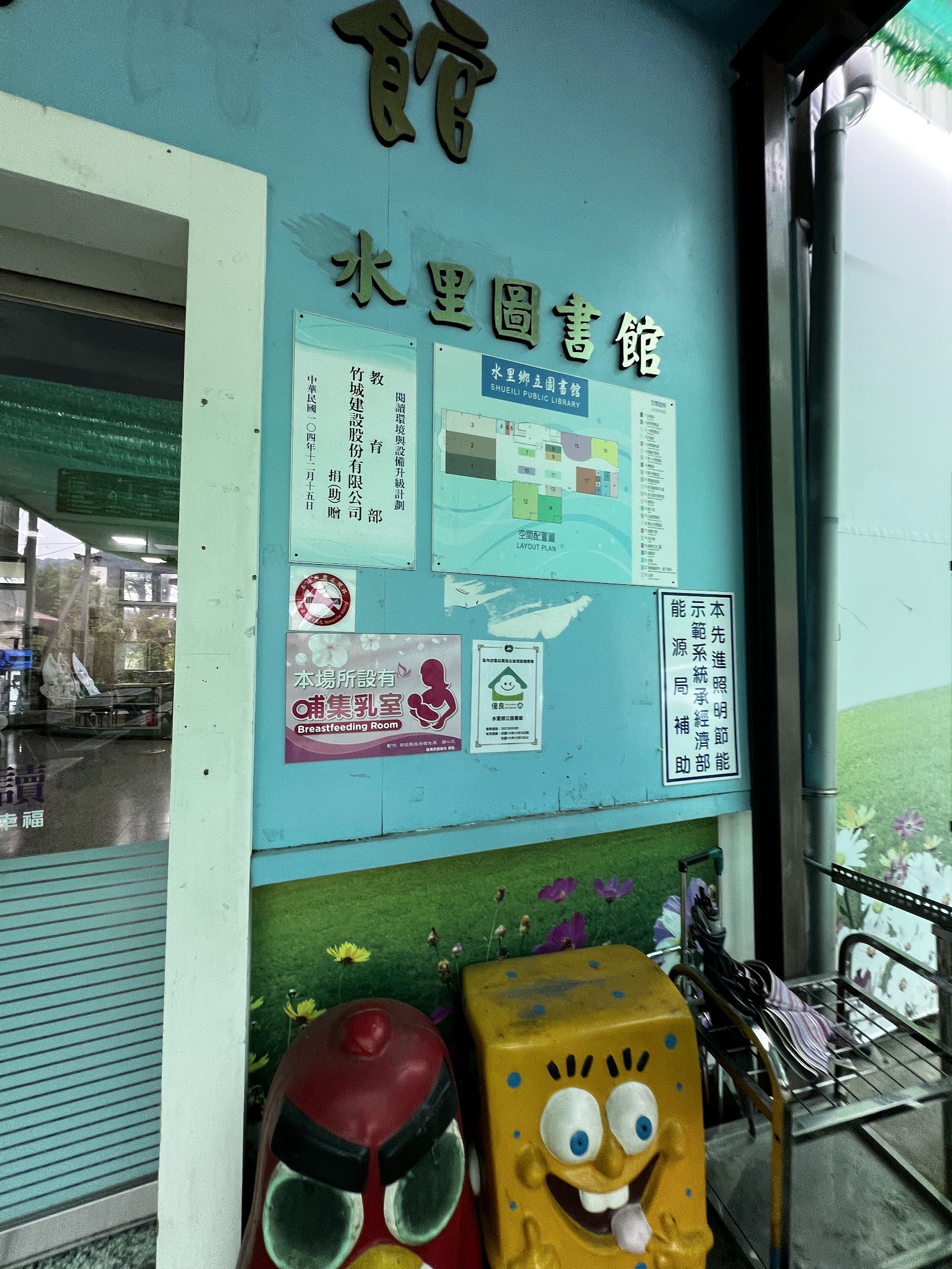 水里圖書館入口木質招牌字樣近照,牆上貼有公告與館內配置圖