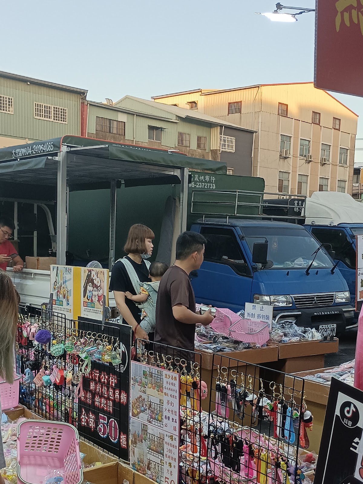 水上夜市攤位擺滿髮飾與鑰匙圈小物，攤商正在整理商品