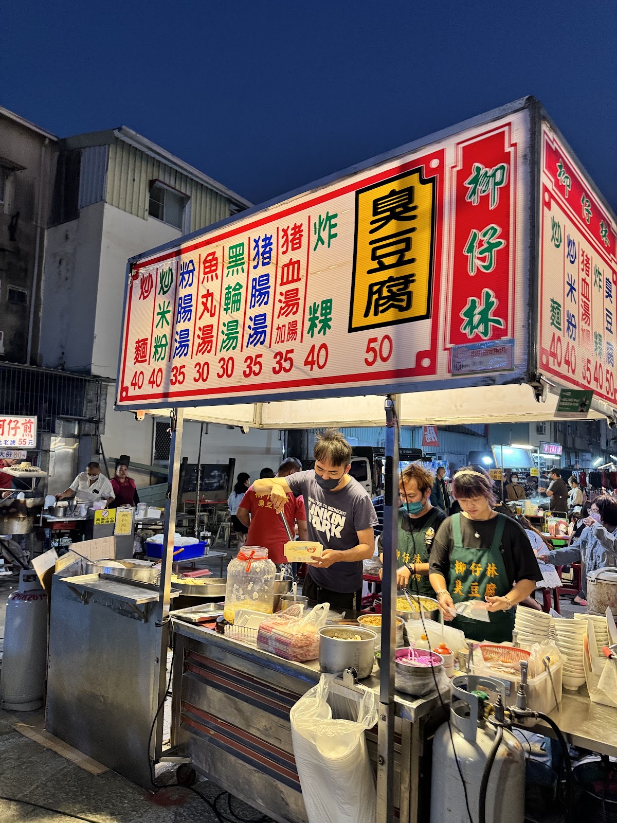 水上夜市小吃攤招牌寫著炸豆腐、臭豆腐、各式湯品，老闆正在備餐