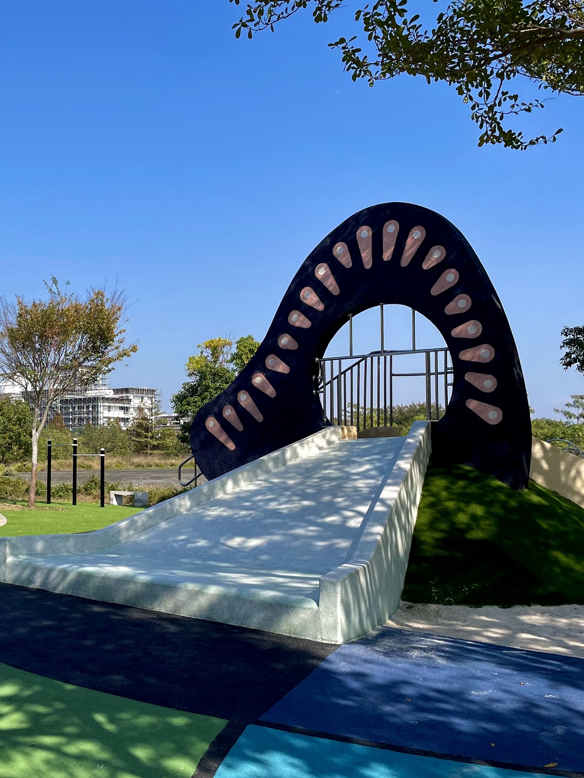 溪東公園造型滑梯，黑白色外觀呈拱門狀，前方為草地緩坡