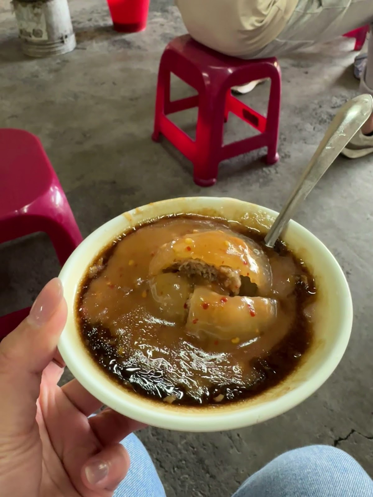 捧在手中的肉圓特寫，醬料與蒜泥淋滿表面，香氣四溢