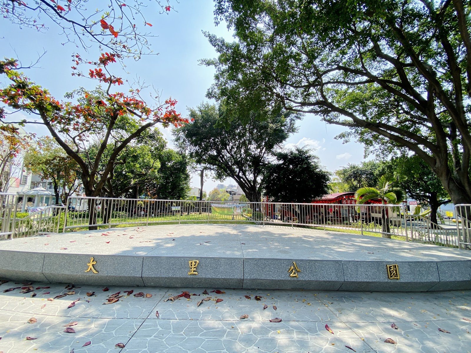 大里公園入口石刻金字招牌，旁邊盛開艷紅刺桐花