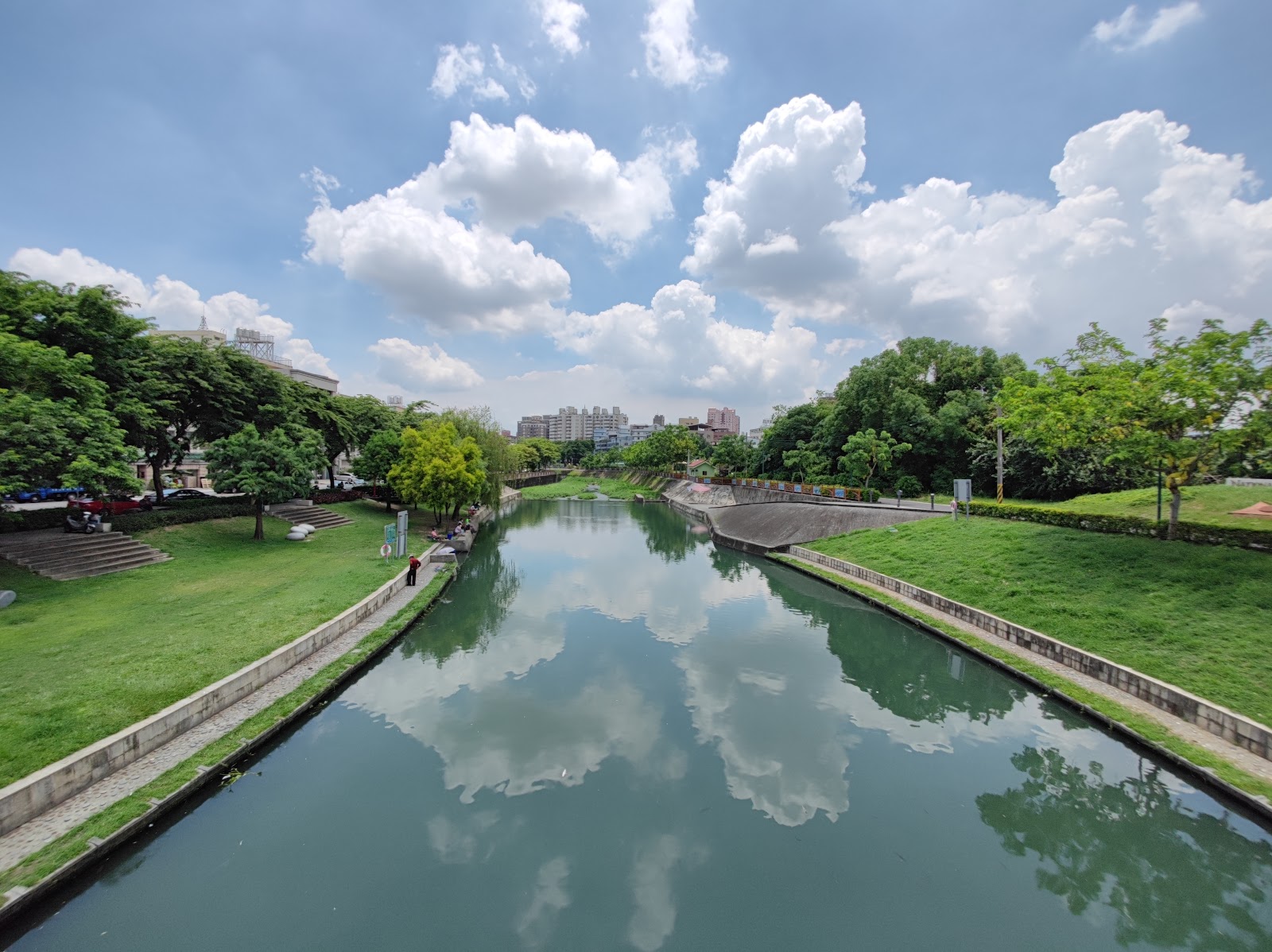 興大康橋運河水面如鏡，倒映藍天白雲，兩岸綠意步道