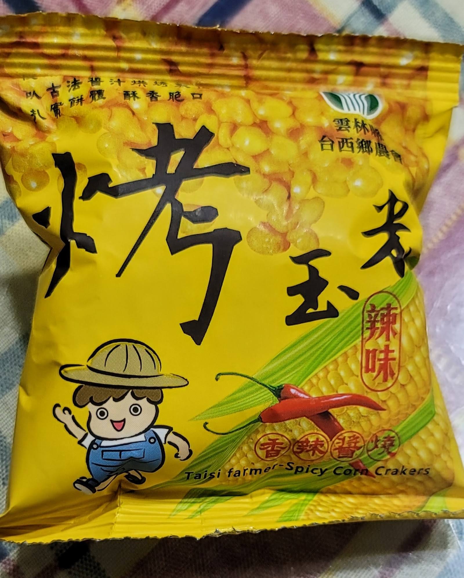 辣味口味包裝袋特寫,印有玉米與辣椒圖案及Taisi farmer Spicy Corn Crackers英文字樣