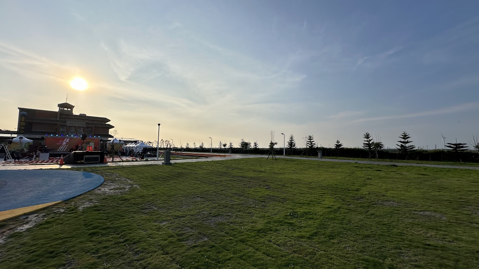 鄉公所廣場旁大片綠地,遠方沿海風力發電機林立,夕陽天空