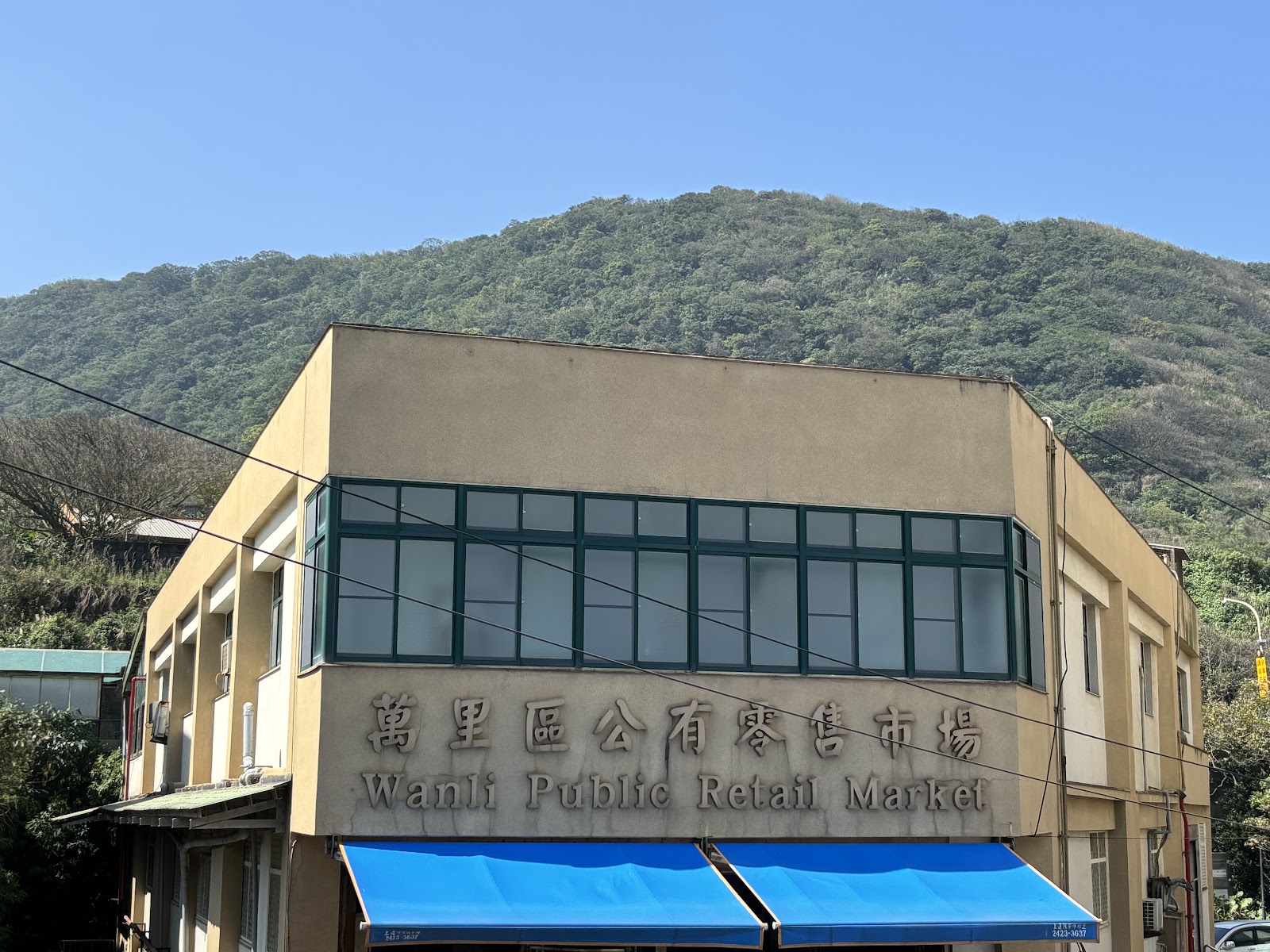 萬里公有零售市場建築外觀，牆面可見中英文招牌「Wanli Public Retail Market」