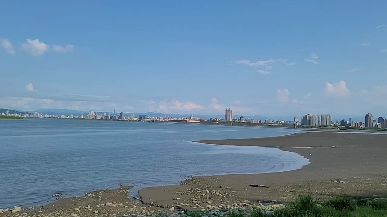 五股獅子頭山水匯集廣場所在的淡水河與基隆河匯流沙洲遠景,對岸台北市天際線含101大樓