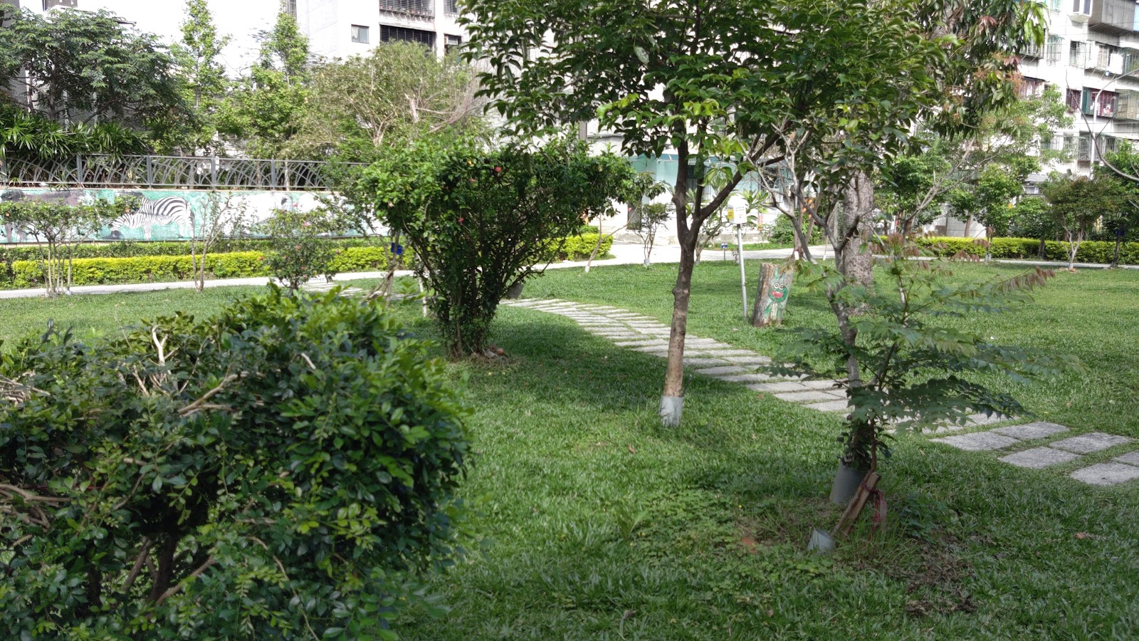 德音休閒廣場綠意草坪步道，石板小徑穿過灌木花叢