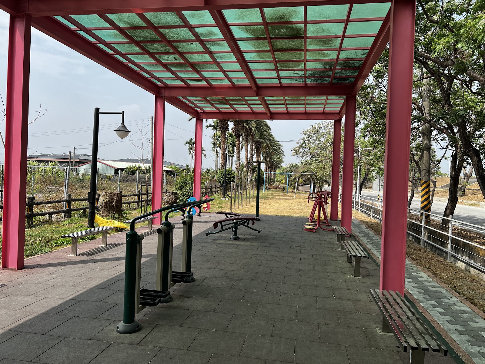 新園龍洲公園紅色遮棚運動遊具區，棕櫚樹林蔭