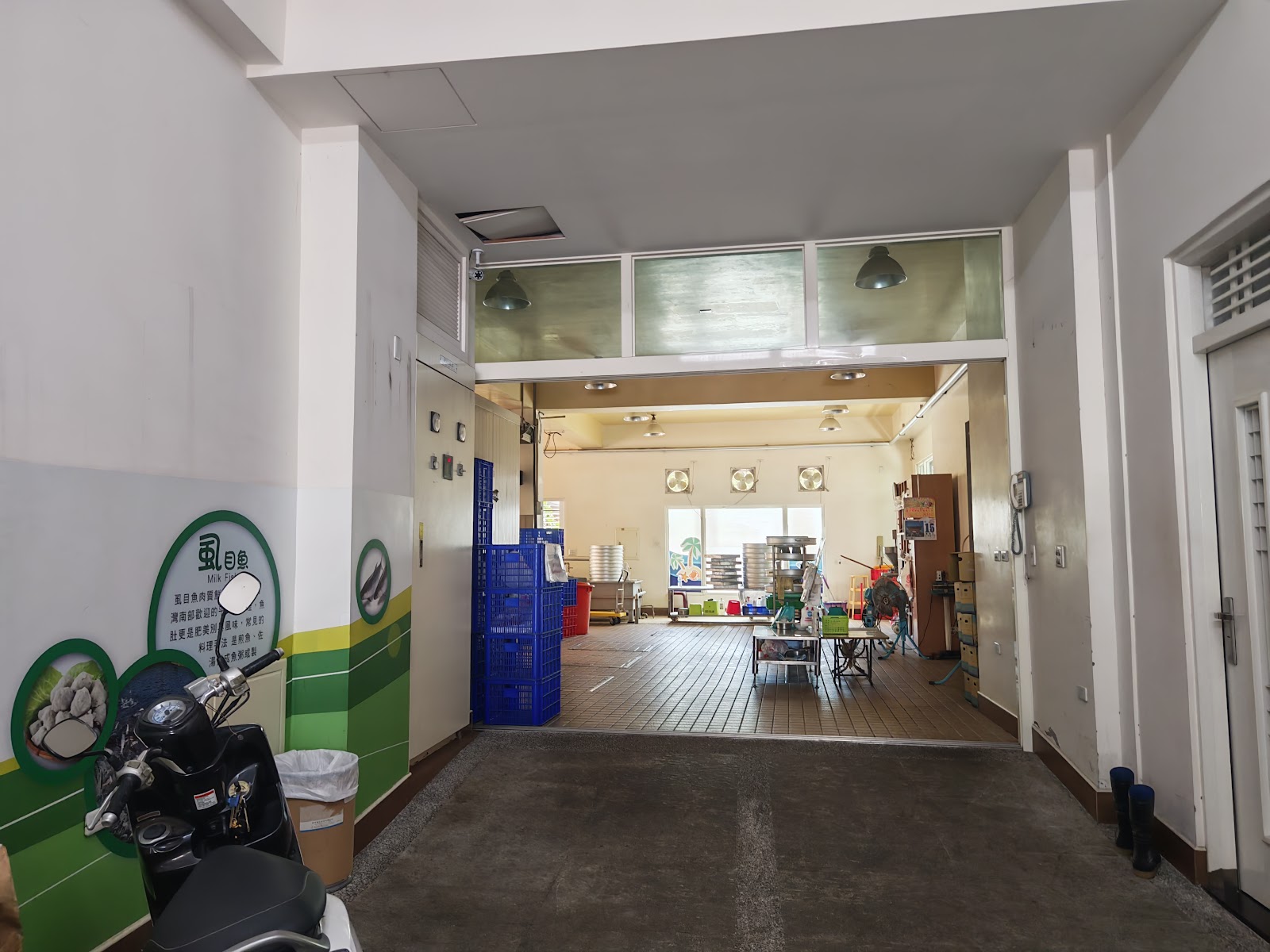 店內加工廠一隅，牆面有虱目魚知識看板與工作空間