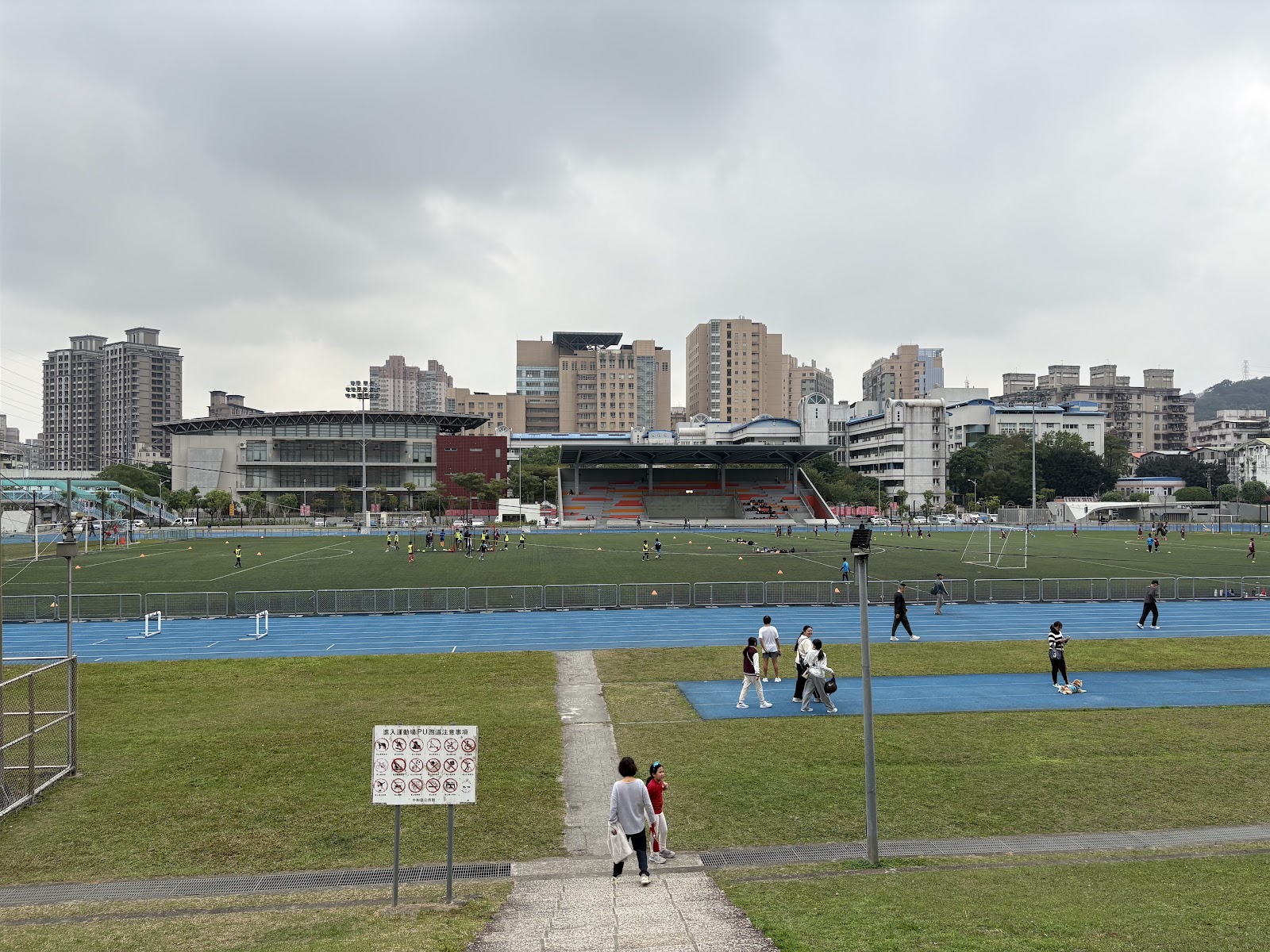 田徑運動場跑道與足球草皮,遠處城市天際線作為背景,視野遼闊